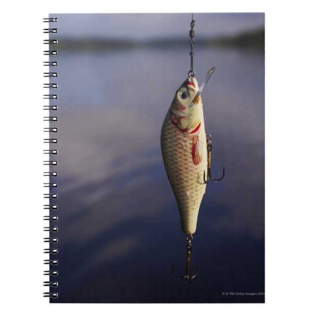 fishing lure in front of water spiral notebook (Front)
