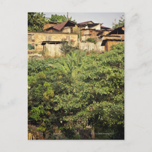 Focus on foreground trees. Jungle village near Postcard