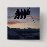 Four snowboarders are silhouetted on a ski lift