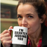 Funny Coffee Mug:  SILENTLY JUDGING YOU Coffee Mug<br><div class="desc">Introducing the hilarious "I'm Silently Judging You" coffee mug, the perfect addition to your morning routine for anyone with a sense of humour! This mug is perfect for those who care too much about grammar, punctuation, and syntax, and just can't help but judge others for their linguistic shortcomings. Featuring a...</div>