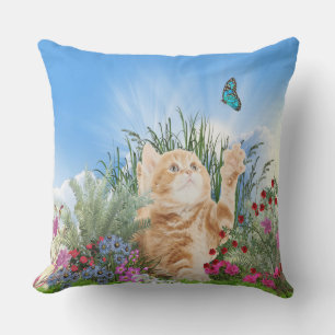 Ginger kitten playing with a butterfly outdoor cushion