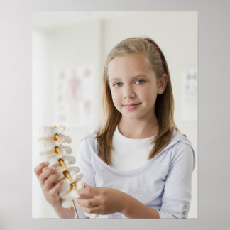 Girl holding model of spine in doctors office poster