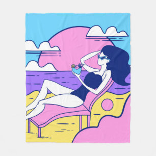 girl sunbathes on the beach with a cocktail in han fleece blanket