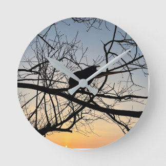 Golden Sunset Silhouette: Bird on Tree Branches Round Clock