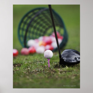 Golf ball on tee beside golf club poster