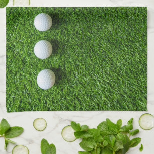 Golf Balls are on green grass Tea Towel