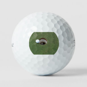 Goofball sitting on lip of hole. golf balls