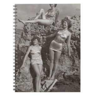 GRAYSCALE PHOTO OF THREE WOMEN STANDING AND SITTIN NOTEBOOK