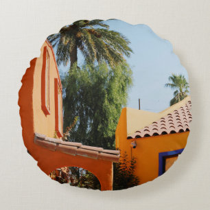 Green palm tree beside brown concrete building in round cushion