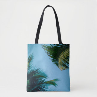 Green palm tree under blue sky in the morning tote bag