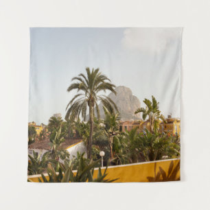 Green palm trees near brown concrete building in t tapestry