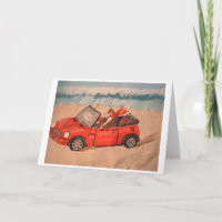 Greyhound in red convertible car at the Beach