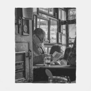 GREYSCALE PHOTO OF MAN SITTING WHILE READING NEWSP FLEECE BLANKET