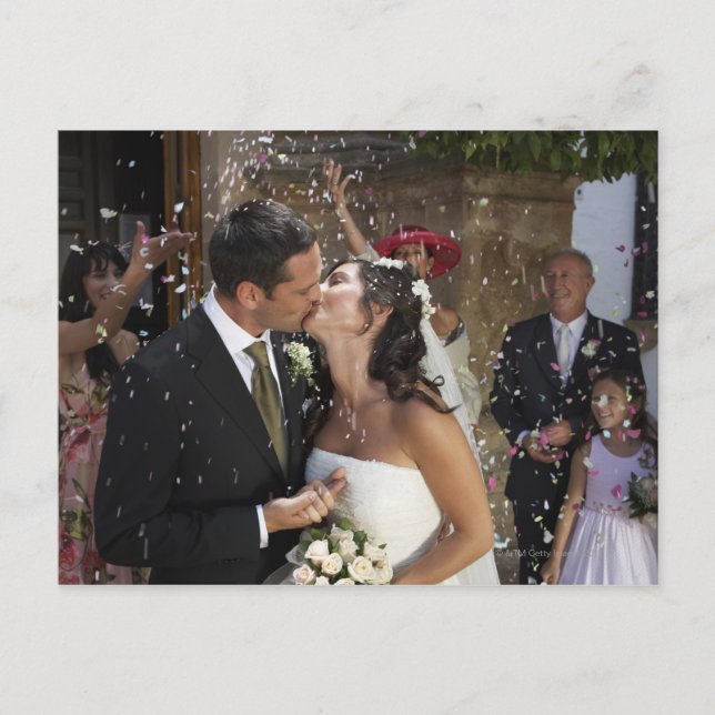 Guests throwing confetti over kissing bride and postcard (Front)