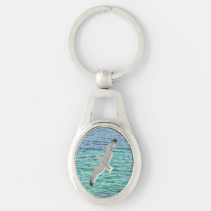 Gull flying above a sea key ring