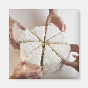 Hands pulling slices from cake magnet
