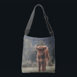 Highland cow calf autumn grass field crossbody bag<br><div class="desc">Highland cow calf autumn grass field photograph. Stunning young calf of highland Scottish cattle on an autumn grassy field with muted colours. Beautiful dark hairy orange coat contrasting with light yellow green grass and trees in bokeh in background.</div>