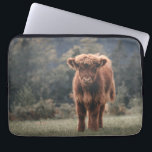 Highland cow calf autumn grass field laptop sleeve<br><div class="desc">Highland cow calf autumn grass field photograph. Stunning young calf of highland Scottish cattle on an autumn grassy field with muted colours. Beautiful dark hairy orange coat contrasting with light yellow green grass and trees in bokeh in background.</div>