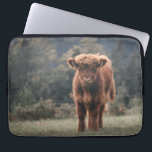 Highland cow calf autumn grass field laptop sleeve<br><div class="desc">Highland cow calf autumn grass field photograph. Stunning young calf of highland Scottish cattle on an autumn grassy field with muted colours. Beautiful dark hairy orange coat contrasting with light yellow green grass and trees in bokeh in background.</div>