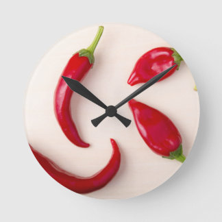 Hot red chilli peppers on a light wooden board round clock