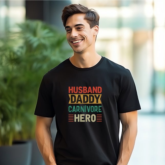 Husband Daddy Carnivore Hero Customisable T-Shirt (Man wearing a black t-shirt with colorful words "Husband, Daddy, Carnivore, Hero")