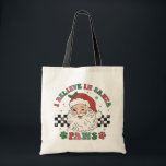 I Believe In Santa Paws Retro Christmas Dog Lover Tote Bag<br><div class="desc">I Believe In Santa Paws Retro Christmas Dog Lover Festive Holiday Tote Bag features the text "I Believe In Santa Paws" in modern script typography surrounding a happy retro Santa on a black and white chequerboard background accented with paw prints. Perfect for Christmas gifts, Christmas parties and holiday celebrations, birthdays...</div>