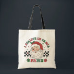 I Believe In Santa Paws Retro Christmas Dog Lover Tote Bag<br><div class="desc">I Believe In Santa Paws Retro Christmas Dog Lover Festive Holiday Tote Bag features the text "I Believe In Santa Paws" in modern script typography surrounding a happy retro Santa on a black and white chequerboard background accented with paw prints. Perfect for Christmas gifts, Christmas parties and holiday celebrations, birthdays...</div>