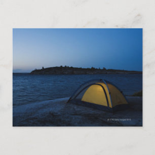 Illuminated tent by sea at dusk postcard