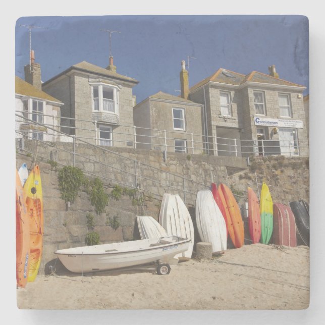 Kayaks and dinghies stacked against seawall at stone coaster (Front)