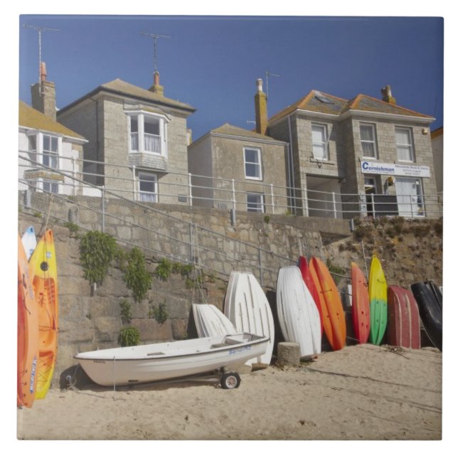 Kayaks and dinghies stacked against seawall at tile (Front)