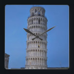 Leaning Tower at Dusk Square Wall Clock<br><div class="desc">This captivating photograph showcases the iconic Leaning Tower of Pisa standing elegantly against a deep blue twilight sky in Pisa. The historic marble tower, famous for its unmistakable tilt, is beautifully illuminated, highlighting its intricate Romanesque arches and layered columns. The soft evening light creates a striking contrast between the glowing...</div>