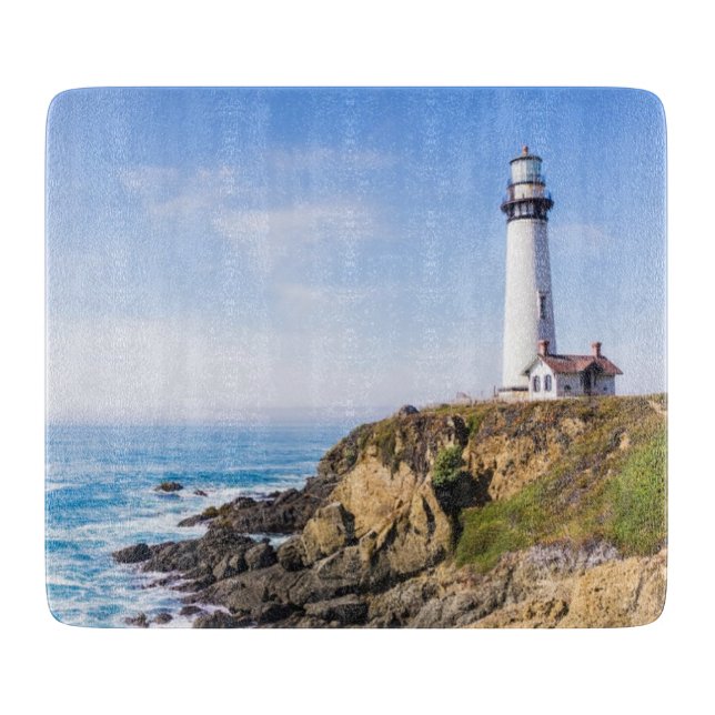 Lighthouse on hill blue sky white house ocean cutting board (Front)