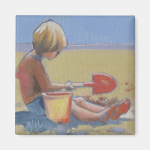 Little boy playing in the sand with a shovel magnet