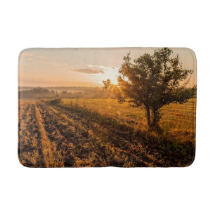 Lonely tree on the foggy field in golden sunrise bath mat