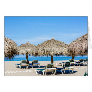 Lounge Chairs And Thatch Umbrellas On Beach