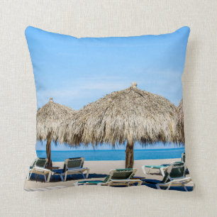 Lounge Chairs And Thatch Umbrellas On Beach Cushion