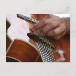 male hand holding pick on acoustic guitar postcard