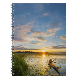 Male kayaker paddling sea kayak on still water spiral notebook