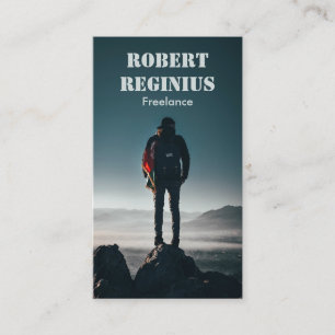 man carrying backpack standing on rock formation business card