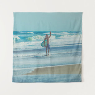 Man carrying surfboard at beach tapestry