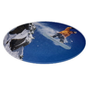 Man on a snowboard jumping off a cornice at cutting board