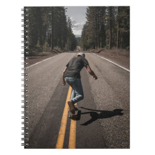 Man playing skateboard on road in the morning notebook