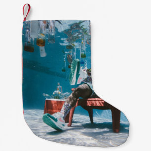 Man sitting on chair underwater with floating bott small christmas stocking