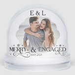 Merry and Engaged Couple Photo Holly Script Snowglobe<br><div class="desc">Celebrate your engagement with holiday magic! This Merry and Engaged custom snow globe features your couple photo surrounded by festive holly accents, elegant script, and delicate snowflakes. It’s the perfect keepsake to mark your first holiday season as fiancés. Add your names, engagement date, or a short love message to make...</div>