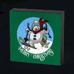 Merry Christmas! Editable Text Skiing Snowman Wooden Box Sign<br><div class="desc">A festive decoration for your wall at Christmas, featuring a cartoon of a jolly snowman with a carrot nose and coal eyes, dashing through the snow on skis, in woolly winter hat and tartan scarf. An upbeat image for Xmas or throughout the winter. Use "Personalise this template" to change the...</div>
