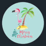 Merry Christmas Pink Flamingo With Palm Tree Classic Round Sticker<br><div class="desc">Festive sticker with a cute illustration of a pink flamingo in a red santa hat. Standing beside a green palm tree on a mound of yellow sand. A fancy swirly christmas tree design is placed beside the text Merry Christmas. Written in the colour pink in a fancy handwritten font. Pastel...</div>