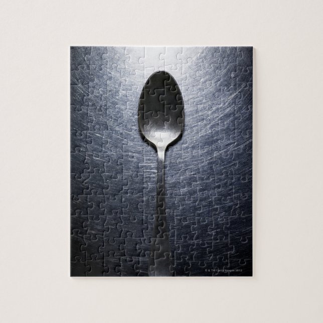 Metal spoon on stainless steel jigsaw puzzle (Vertical)