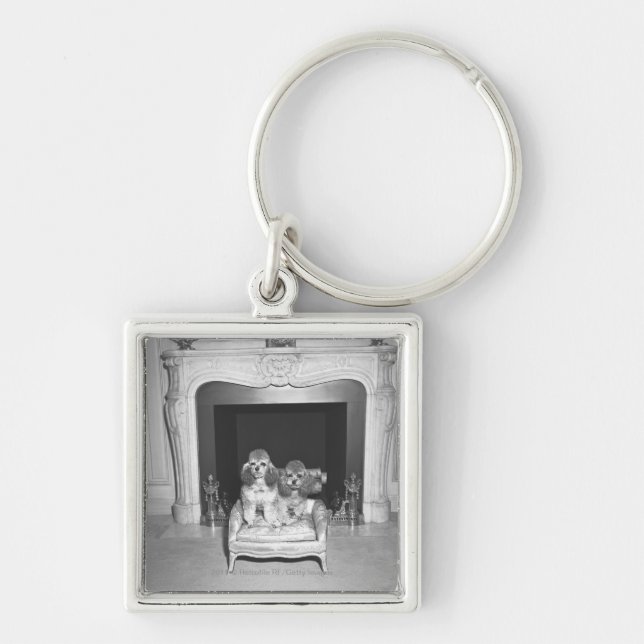 Miniature poodles sitting in front of fireplace key ring (Front)