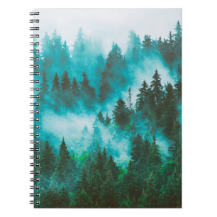 Misty foggy mountain landscape with fir forest and notebook