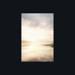 Misty Lake Sunrise Golden Reflection Canvas Print<br><div class="desc">Soft golden sunlight pierces through thick morning mist over a calm lake, creating a luminous path of reflection across the water. Tall reeds line the shore while distant trees fade into the haze, and the sky blends warm peach and rose tones into pale blue-gray. The composition radiates profound stillness, gentle...</div>